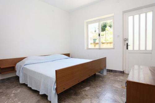 a white bedroom with a bed and a window at Holiday apartments Duba Peljeska, Peljesac - 10230 in Orebić