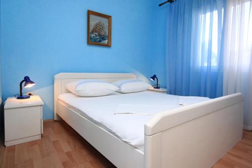 a bedroom with a white bed with blue walls at Apartments with a parking space Orebic, Peljesac - 10171 in Orebić