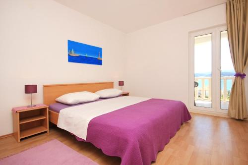 a bedroom with a bed with a purple blanket and a window at Apartments with a parking space Kuciste - Perna, Peljesac - 10161 in Kučište