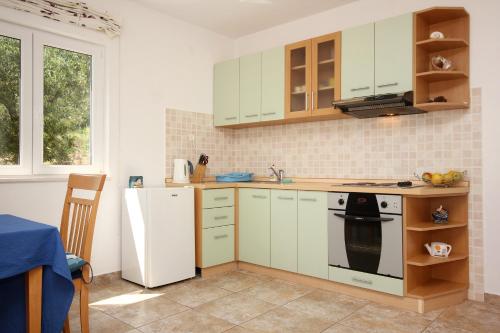a kitchen with white cabinets and a stove and a refrigerator at Apartments with a parking space Kuciste - Perna, Peljesac - 10161 in Kučište