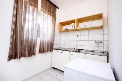 una piccola cucina bianca con lavandino e specchio di Apartments by the sea Viganj, Peljesac - 10187 a Viganj
