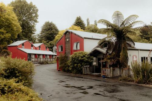 a row of red and white buildings with a palm tree at Waitomo Village Chalets home of Kiwipaka in Waitomo Caves