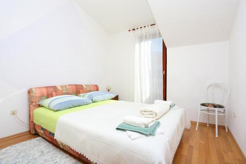 a white bedroom with a bed with blue pillows at Apartments by the sea Podstrana, Split - 9503 in Podstrana