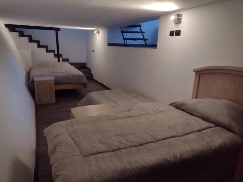 1 dormitorio con 2 camas y escalera en Hermosos departamentos en el centro de Coatepec Veracruz, en Coatepec