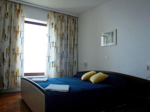 Schlafzimmer mit einem Bett mit blauer Bettwäsche und einem Fenster in der Unterkunft Apartments by the sea Orebic, Peljesac - 10153 in Orebić