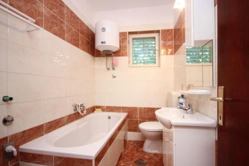 a bathroom with a tub and a toilet and a sink at Apartment Mastrinka 10261b in Trogir