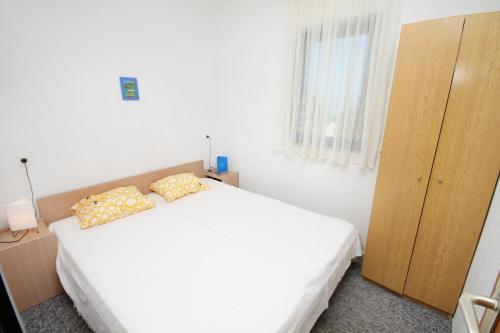 a bedroom with a white bed and a wooden cabinet at Apartments with parking space Njivice, Krk - 9668 in Njivice