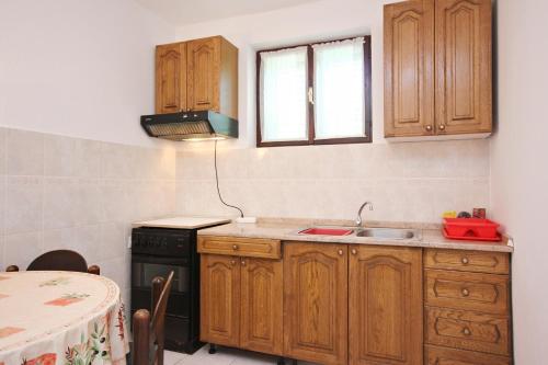 een keuken met houten kasten, een wastafel en een tafel bij Apartments by the sea Loviste, Peljesac - 10182 in Lovište