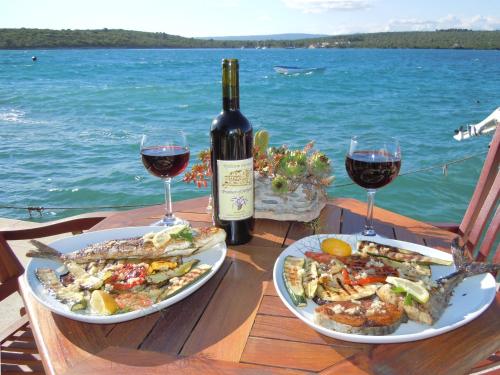 a table with two plates of food and two glasses of wine at Double Room Loviste 10181a in Lovište