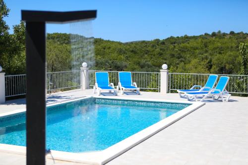 una piscina con sedie a sdraio blu accanto ad essa di Family friendly house with a swimming pool Zavalatica, Korcula - 9476 a Zavalatica