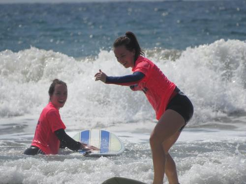 two young girls playing in the ocean on a surfboard at Vikara in Olón