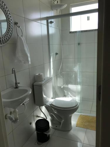 a white bathroom with a toilet and a sink at Villa das aguas -Praia do saco -Próximo as lagoas dos Tambaquis e Mangue Seco -térreo in Estância