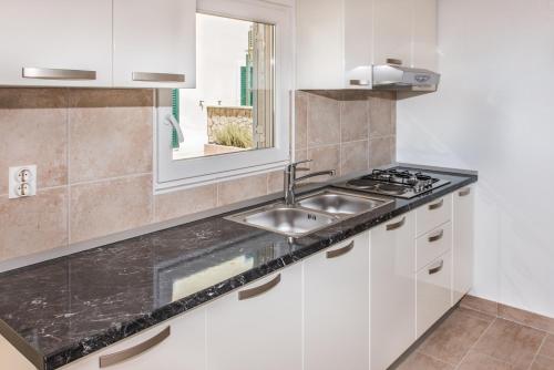 eine Küche mit weißen Schränken, einem Waschbecken und einem Fenster in der Unterkunft Apartments by the sea Rogac, Solta - 11655 in Grohote