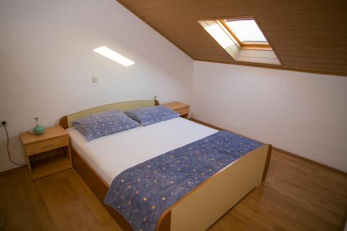 a bedroom with a bed with blue pillows and a window at Apartments by the sea Zubovici, Pag - 9678 in Zubovići
