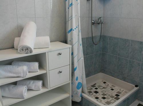 uma casa de banho com um chuveiro e um armário branco com toalhas em Apartment Lukoran 11672a em Lukoran