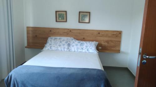 1 dormitorio con cama blanca y cabecero de madera en Residencial Marbella en Bombinhas