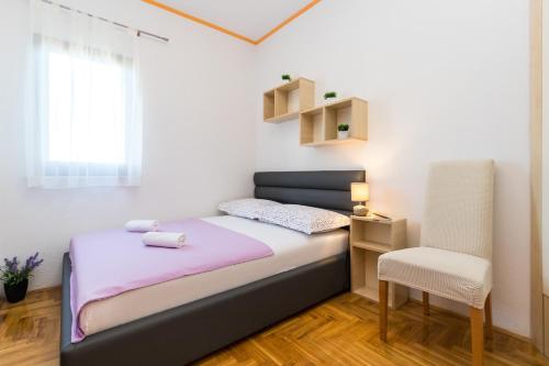 ein kleines Schlafzimmer mit einem Bett und einem Stuhl in der Unterkunft Apartments with a parking space Kastel Kambelovac, Kastela - 11678 in Kaštela