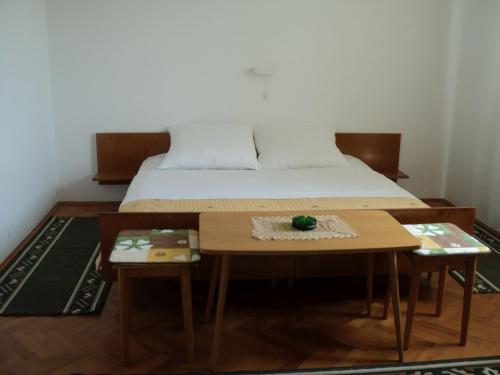 a bedroom with a bed and a table with two tables at Double Room Banjol 11716b in Rab