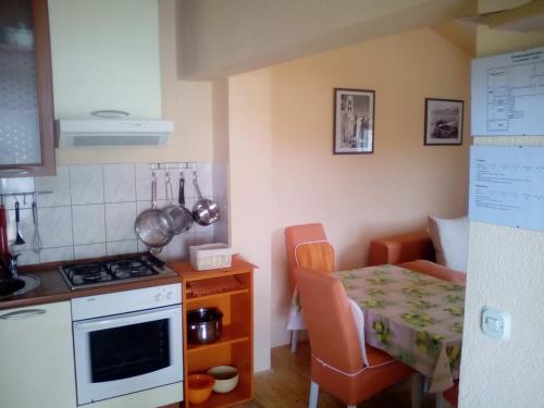 kuchnia ze stołem oraz niewielka kuchnia ze stołem i kuchenką w obiekcie Apartments with a parking space Pirovac, Sibenik - 11746 w mieście Pirovac
