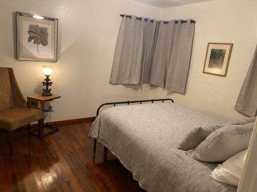 een slaapkamer met een bed, een stoel en een raam bij Lake Murray House in La Mesa