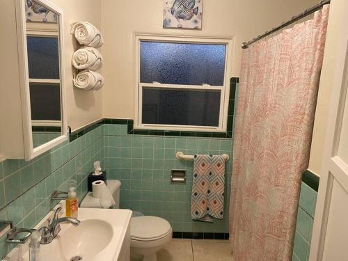 een badkamer met een wastafel, een toilet en een raam bij Lake Murray House in La Mesa