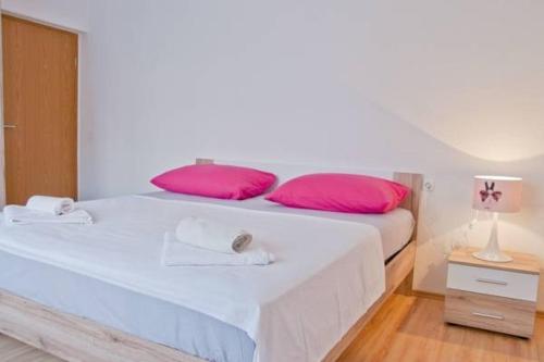 a large white bed with pink pillows in a room at Apartments with a parking space Split - 11726 in Split