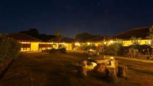 a yard at night with a building with lights at Hotel Peace Island Taketomijima in Taketomi