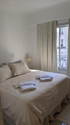 un letto bianco con due asciugamani sopra con una finestra di Soleado Pueyrredón a Salta