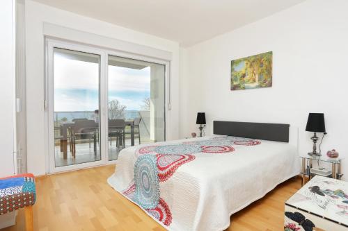 a white bedroom with a bed and a balcony at Apartments with a parking space Split - 11863 in Split