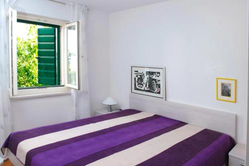 a bedroom with a purple bed in a white room at Holiday house with a swimming pool Plano, Trogir - 11897 in Kastel Stafilic