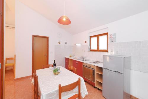 uma cozinha com uma mesa com uma toalha de mesa branca em Apartment Bozava 11896a em Božava