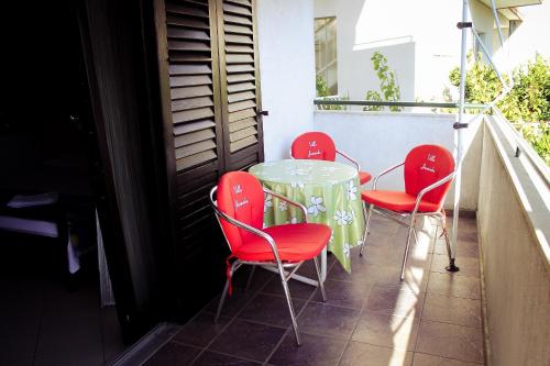 a table and four red chairs on a balcony at Apartments and rooms by the sea Podgora, Makarska - 11893 in Podgora