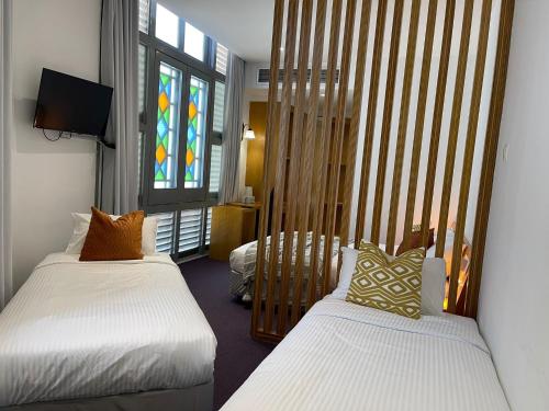 新加坡的住宿－The Assembly Place, A Co-living at Mayo，一间卧室设有两张床和彩色玻璃窗。