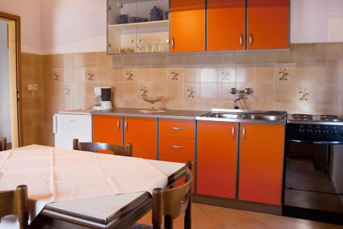 a kitchen with orange cabinets and a table and a sink at Apartments and rooms with parking space Zambratija, Umag - 11875 in Zambratija