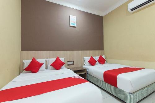 two beds in a hotel room with red pillows at Silibin Times Inn Hotel in Ipoh