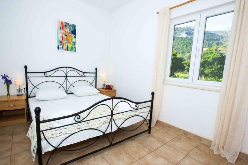 a bedroom with a black bed with a window at Apartments by the sea Zuljana, Peljesac - 12058 in Žuljana