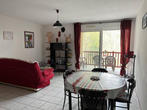 un salon avec une table et un canapé rouge dans l'établissement Appartement T2 calme avec terrasse et parking à Cambo-les-Bains, proche centre et thermes - FR-1-495-109, à Cambo-les-Bains