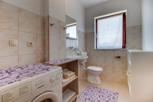a bathroom with a washing machine and a toilet at Apartments with a parking space Nerezine, Losinj - 12149 in Nerezine