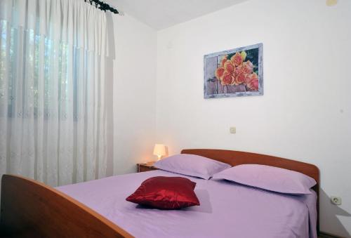 ein Schlafzimmer mit einem Bett mit einem roten Kissen darauf in der Unterkunft Seaside house for families with children Zatoglav, Rogoznica - 12212 in Rogoznica