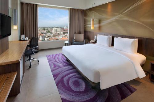 a hotel room with a large white bed and a desk at Holiday Inn Bandung Pasteur by IHG in Bandung
