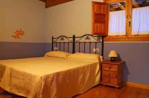 a bedroom with a large bed and a night stand at Casa Rural Los Barreros in San Cristóbal de Segovia