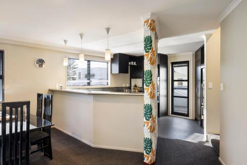 cocina y sala de estar con barra y mesa en Pacific Escape - Downtown, Beach & Sea Views, en Mount Maunganui