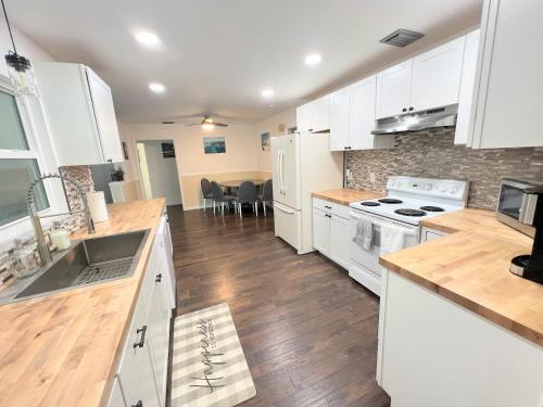 uma cozinha com armários brancos e pisos em madeira em Dream Vacation Home w Heated Pool Close to Beaches Clearwater St Pete Sleeps 14 em Seminole