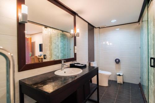 a bathroom with a sink and a mirror and a toilet at New Champa Boutique Hotel in Vientiane