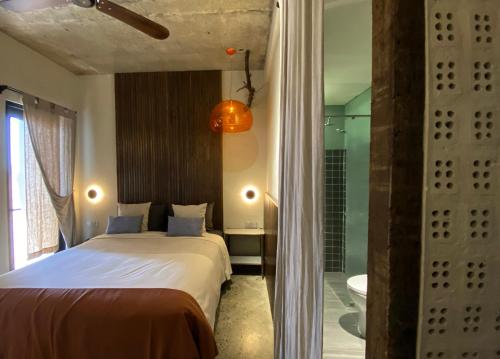 a bedroom with a bed and a bathroom with a shower at Kaia Gallery Hotel Hoi An in Hoi An