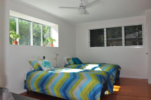 a bedroom with two beds and two windows at Double 10 in Rainbow Beach