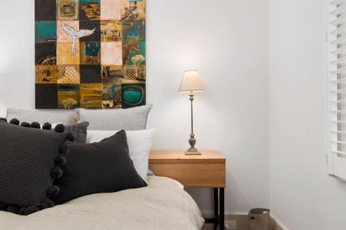 een slaapkamer met een bed en een tafel met een lamp bij Tori's Luxury Historic Cottage - Walk Salamanca in Hobart