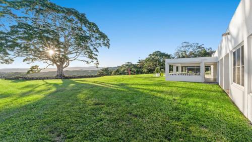 a large grassy yard next to a white building at Amileka - luxury 25 acre estate with pool in Federal