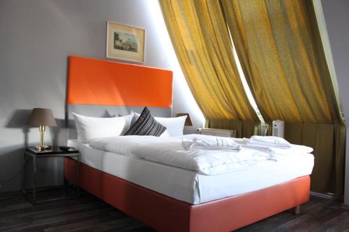 a bedroom with a large bed with an orange headboard at Hotel Arena Inn - Berlin Mitte in Berlin