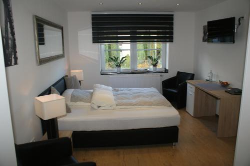 een slaapkamer met een bed, een bureau en 2 ramen bij Brommler Mühle in Gangelt